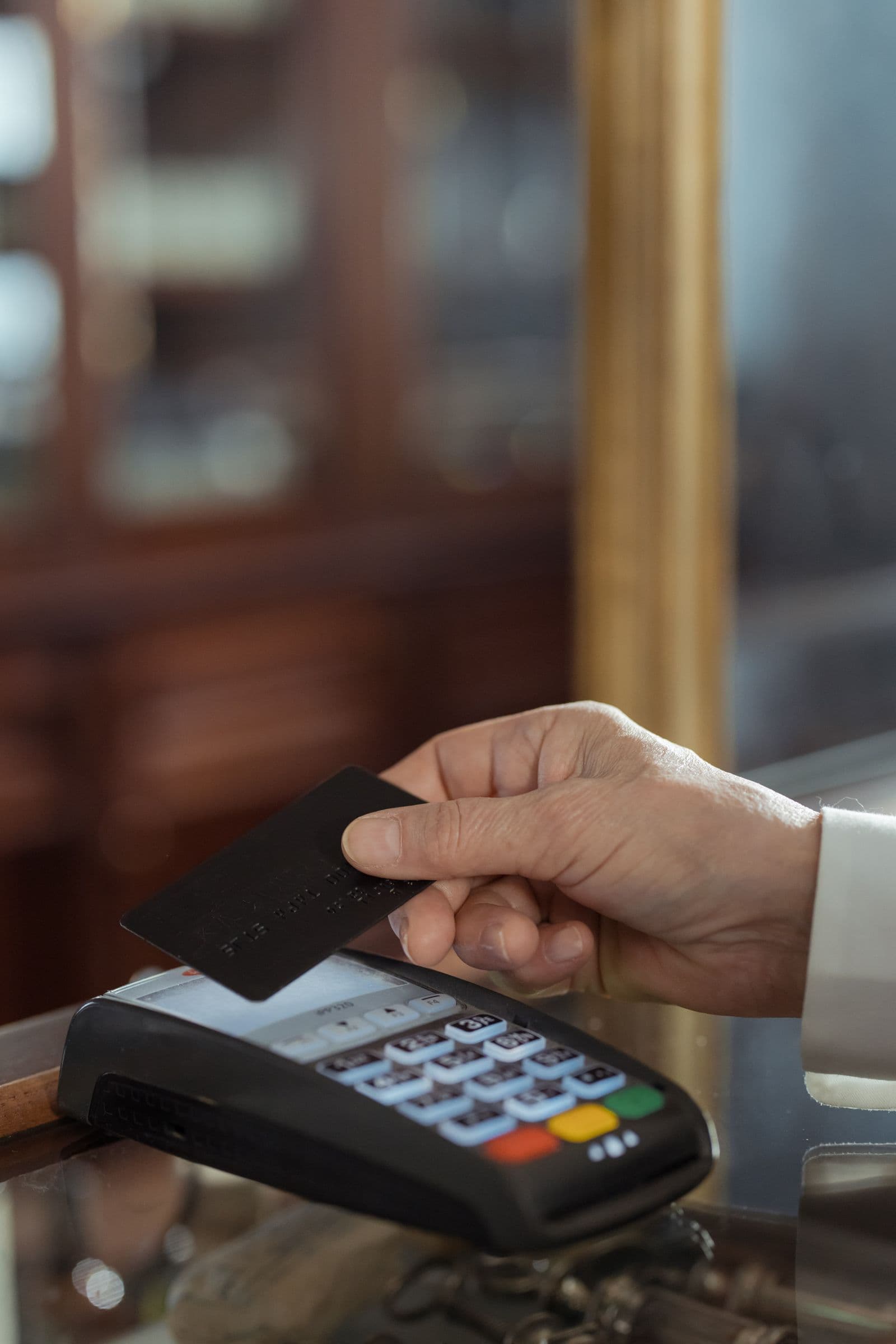 Mão a pagar com um cartão num terminal de pagamento
